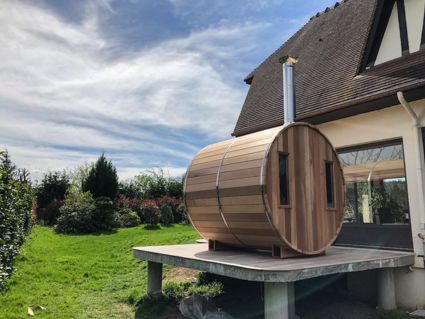 Saunabarrel op een verhoogd terras, sauna voorzien van een langere schoorsteen.